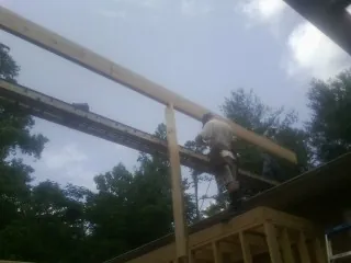 Carpenter setting a ridge beam over a new addition frame — Ice Dam Removal by Roofing Brothers in Wana
