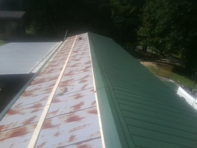 Old rusted panels beside newly installed green metal roofing — Wind Damage Roof Repair by Roofing Brothers in Wana