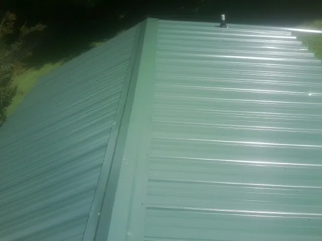 New green metal panels meeting at the ridge of a roof — Flat Roof Repair work by our crew in Wana