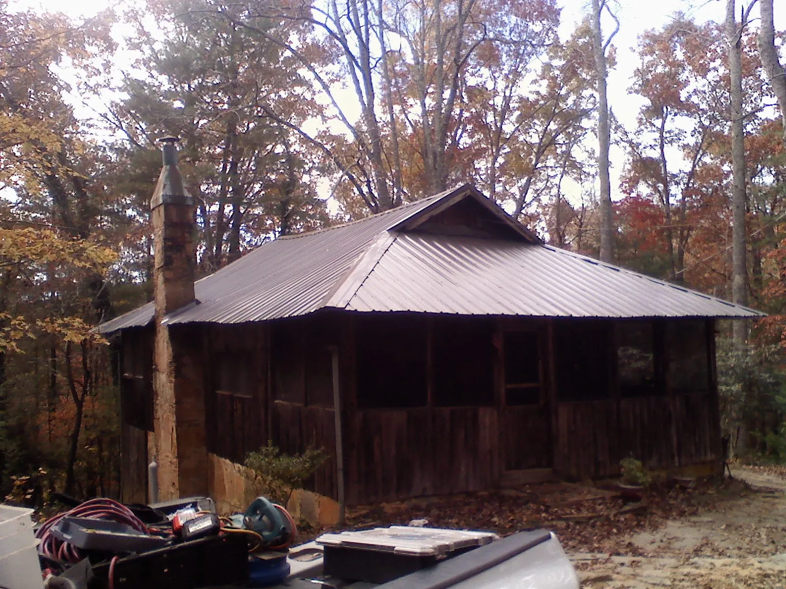 Brown metal hip roof on an old cabin with a stone chimney in Wana