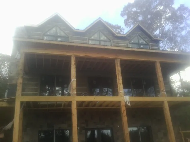 Dormers and porch framing on a large log home under construction — Roof Coating work by our crew in Wana