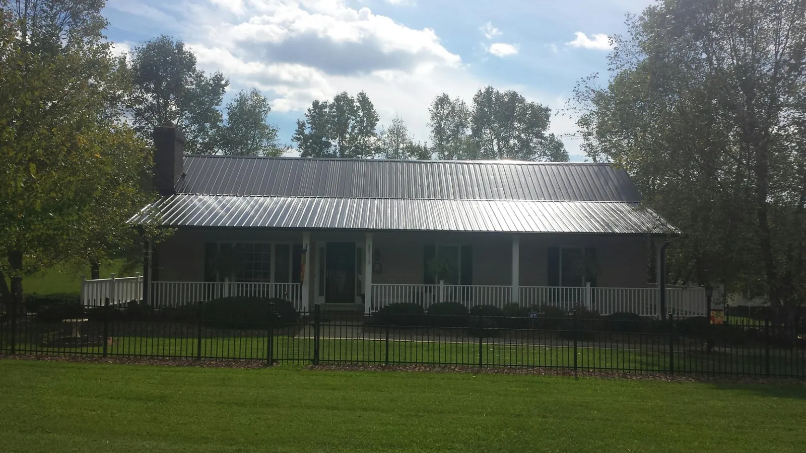 Gray metal roof on a brick ranch with a full width front porch — Gutter Guard Installation work by our crew in Wana