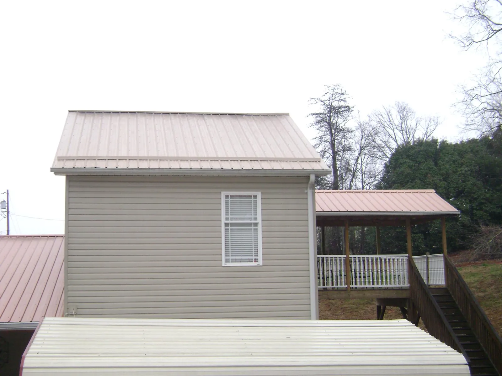 Tan metal roofs on a two story addition and attached porch, from a Roof Replacement job in Wana