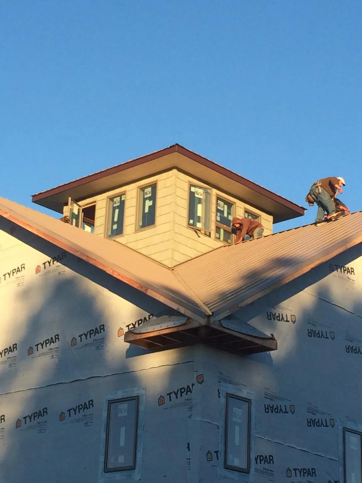 Roofers working around a rooftop cupola on a new metal roof at sunset — Roof Waterproofing in Wana by Roofing Brothers